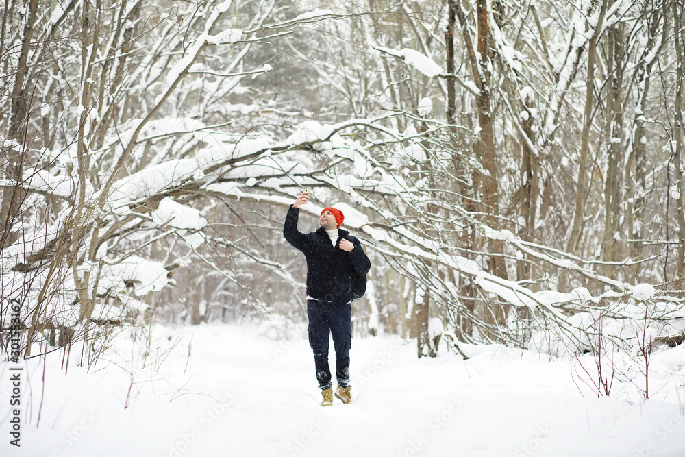 A man in the winter in the forest. A tourist with a backpack goes through the woods in winter. Winter ascent.