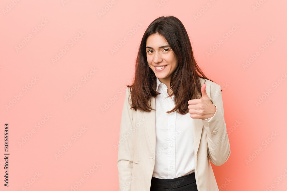 Young brunette business woman against a pink background smiling and raising thumb up Young brunette business woman against a pink background smiling and raising thumb up