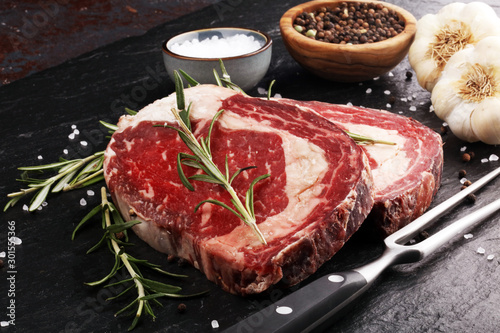 Raw fresh meat Ribeye Steak, seasoning and meat fork on rustic background
