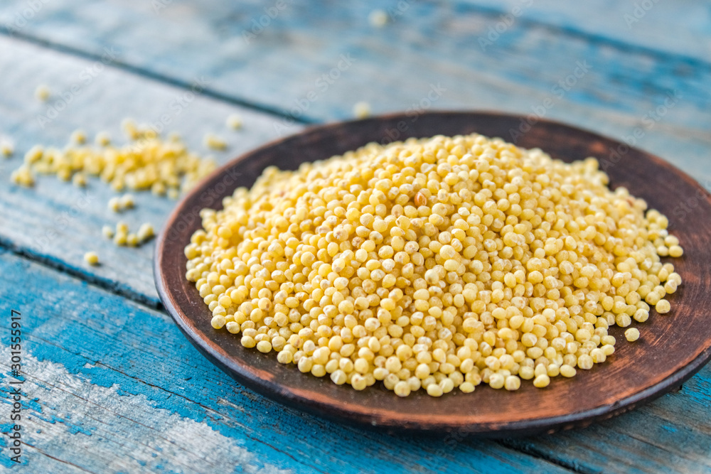 Dry yellow millet in a bowl on a background of old blue boards. Dry yellow millet in a bowl on a background of old blue boards.