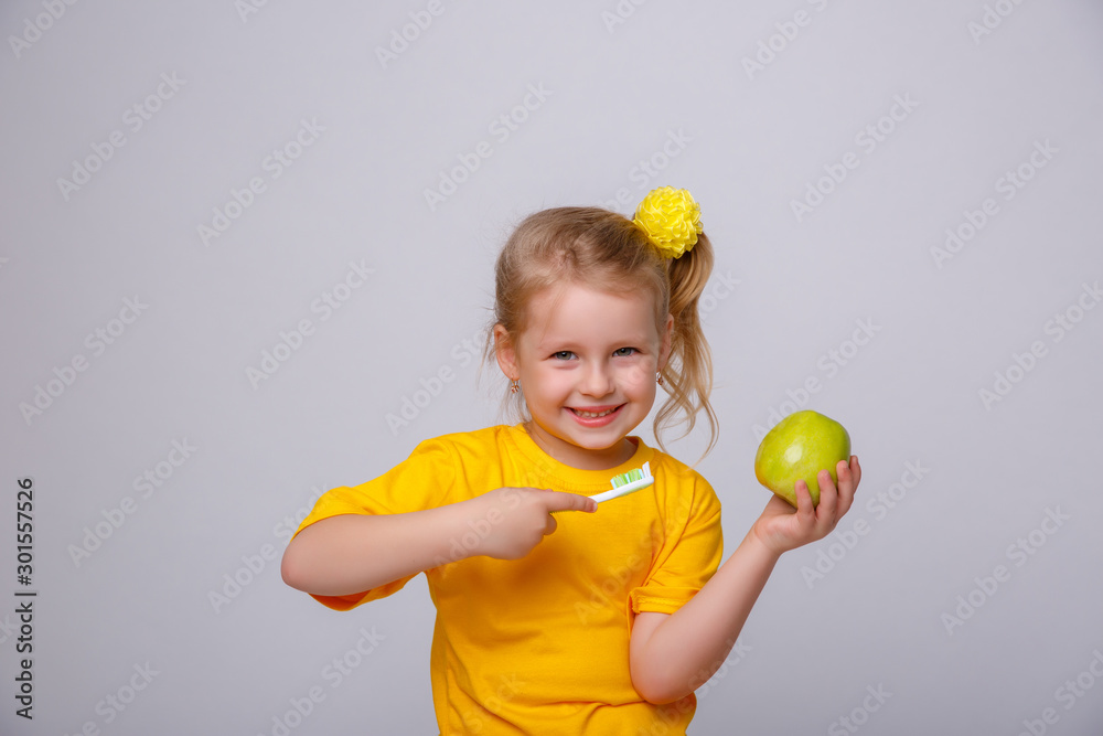 little girl holding Apple and toothbrush on white background little girl holding Apple and toothbrush on white background