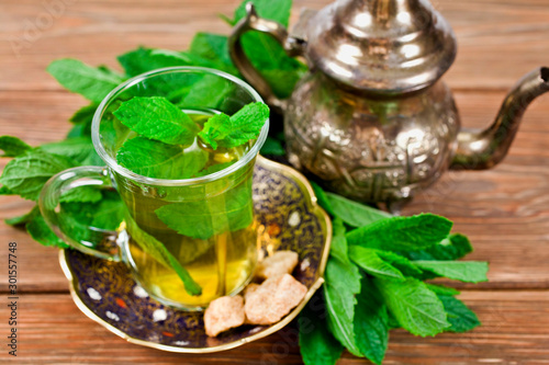 Moroccan tea with green mint leaves on a wooden background