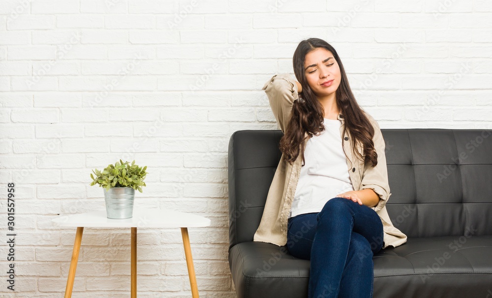 Young arab woman sitting on the sofa suffering neck pain due to sedentary lifestyle. Young arab woman sitting on the sofa suffering neck pain due to sedentary lifestyle.