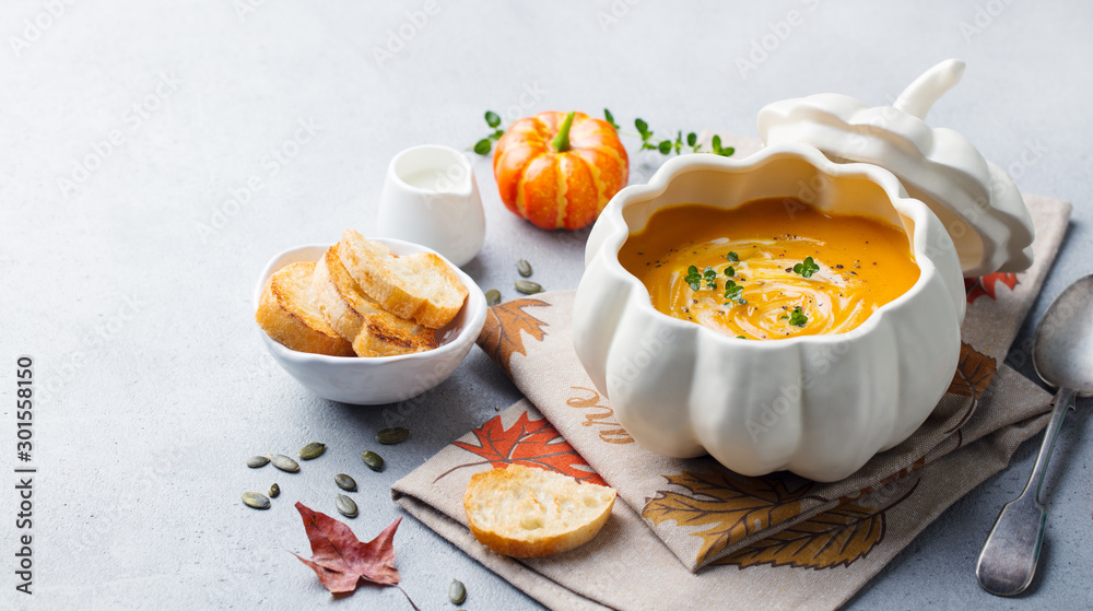 Pumpkin and carrot cream soup in bowl on grey stone background. Copy space.