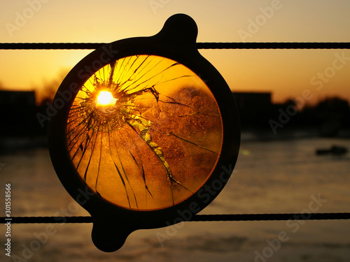 The Sun Sets through a hole made in a lens which is attached to a fence at the Ropetackle deveopment in Shoreham-by-Sea which overlooks the River Adur in West Sussex.