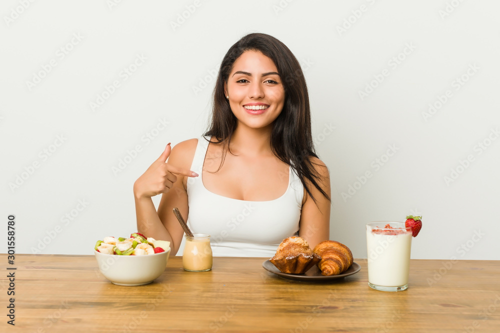 Young curvy woman taking a breakfast person pointing by hand to a shirt copy space, proud and confident Young curvy woman taking a breakfast person pointing by hand to a shirt copy space, proud and confident