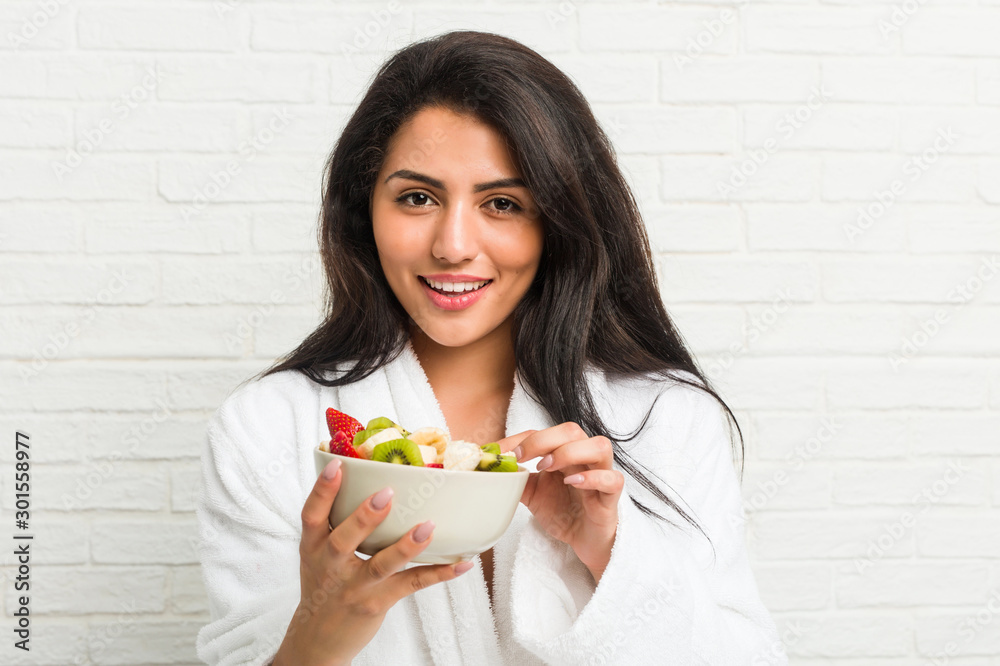 Young hispanic woman eating a fruit bowl on the bed Young hispanic woman eating a fruit bowl on the bed