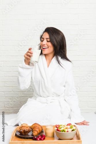 Young hispanic woman having breakfast on the bed