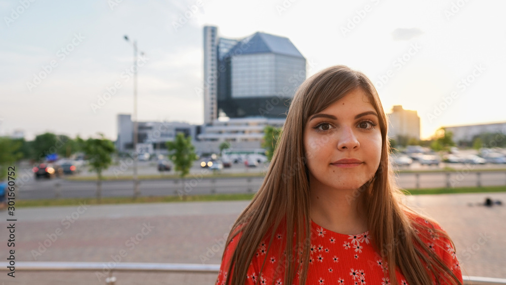 Close Up portrait of a Happy young beautiful woman. Pretty girl dreaming. Looking in camera. City ​​park background.Concept of dreams and smart thoughts