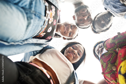 Group of five african college students spending time together on campus at university yard. Black afro friends studying. Education theme. View from down.