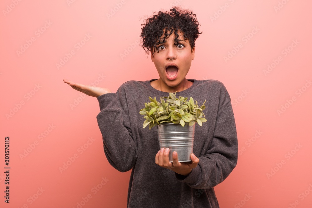 Φωτογραφία Young african american woman holding a plant cheerful and confident showing ok gesture