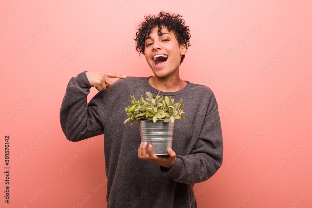 Φωτογραφία Young african american woman holding a plant showing fist to camera, aggressive facial expression