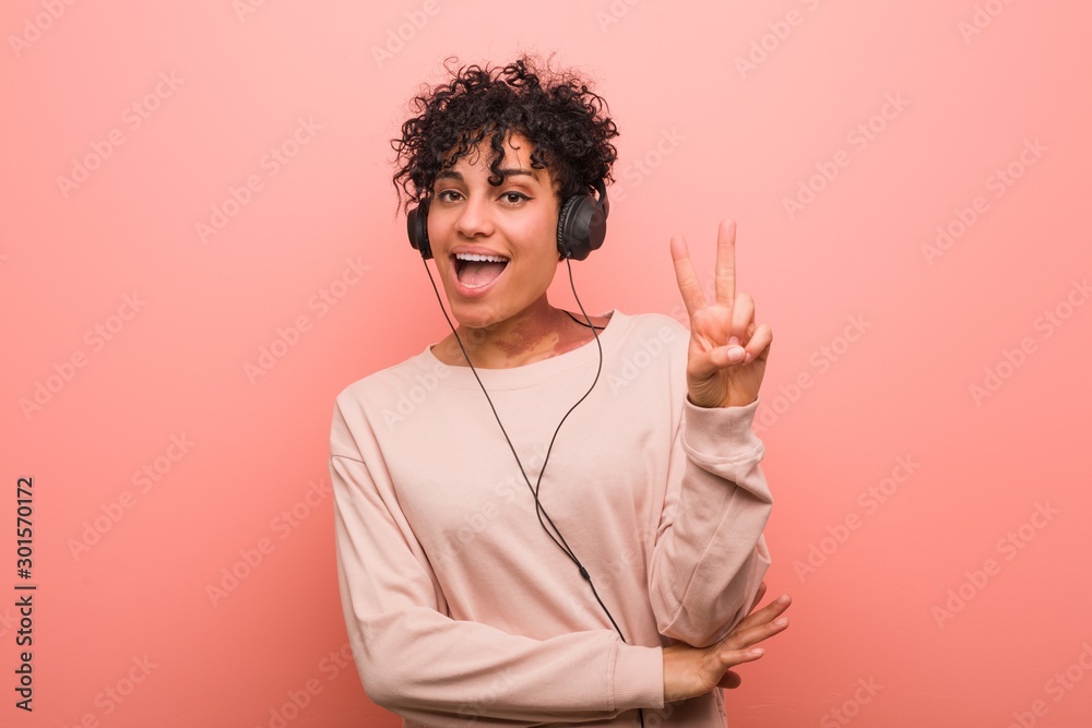 Φωτογραφία Young african american woman listening to music showing number two with fingers