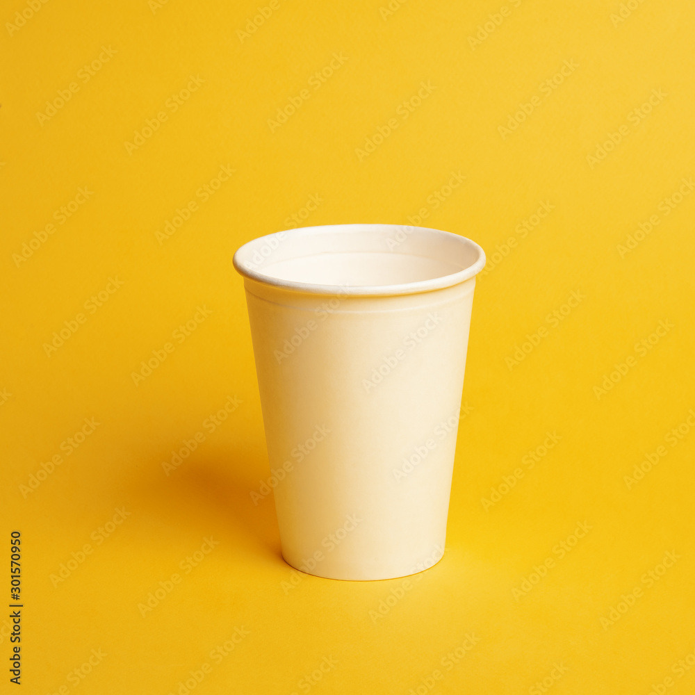 a white plastic cup on a yellow background. a white plastic cup on a yellow background.