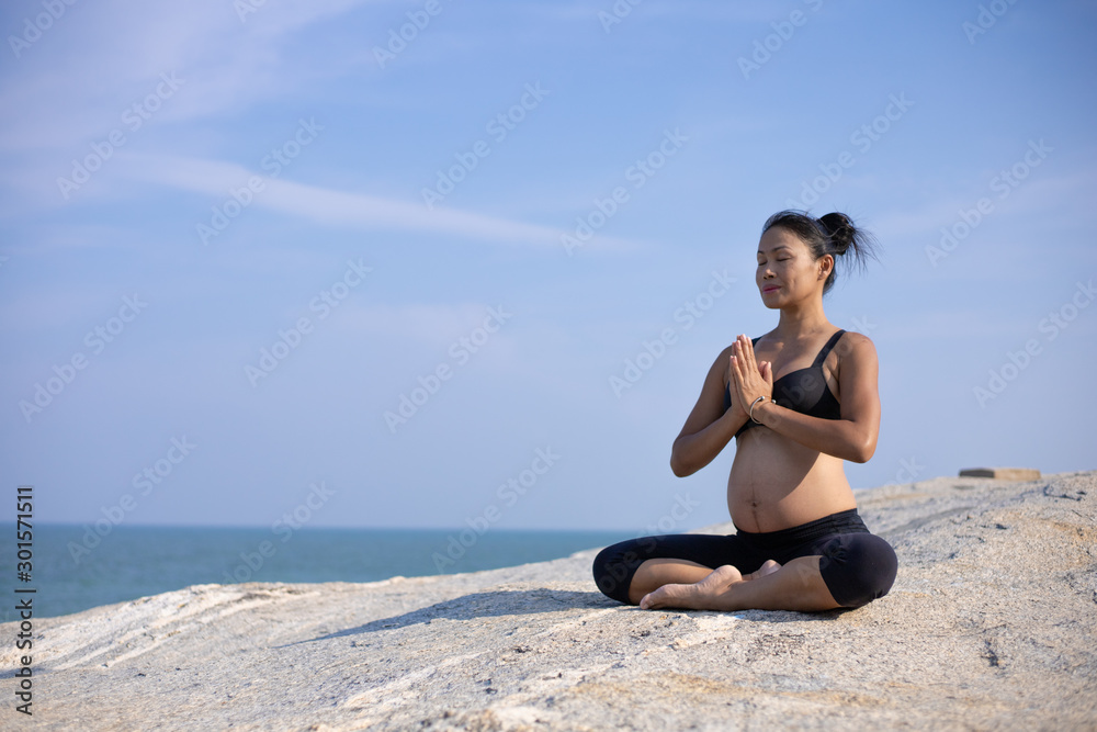Asian pregnant woman yoga on the beach sunset summer time Asian pregnant woman yoga on the beach sunset summer time