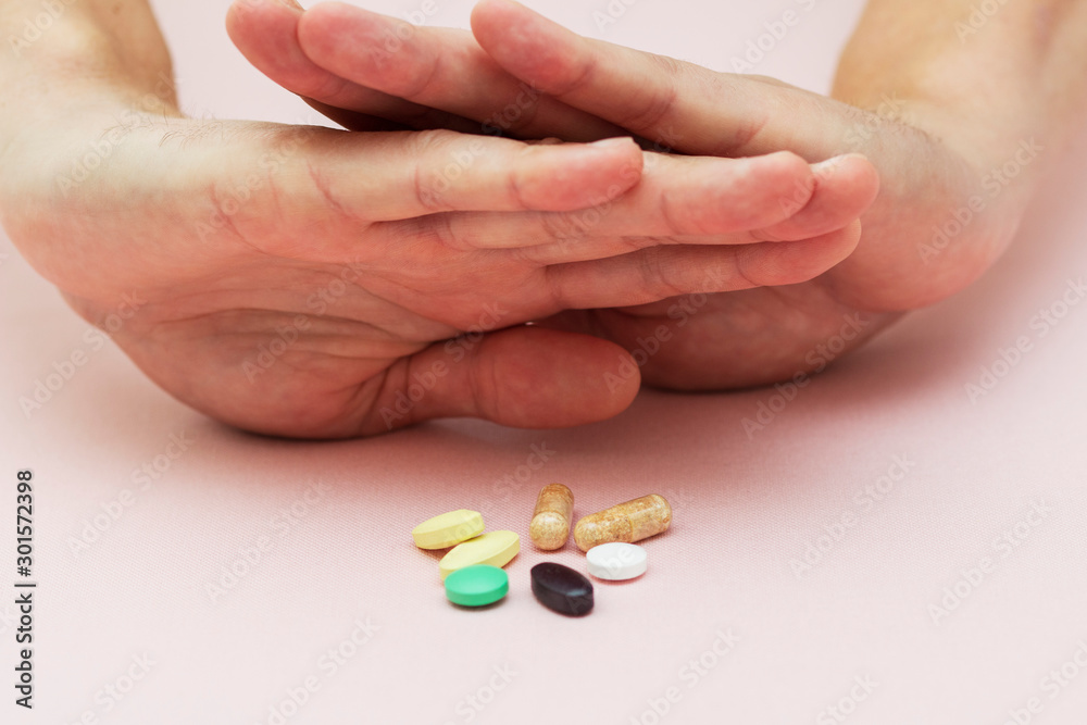 man refuses pills, pills on the table, health, medicine, pink background man refuses pills, pills on the table, health, medicine, pink background