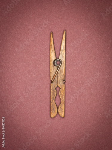 A weathered wooden clothes peg photographed with a ring flash on a textured paper background.