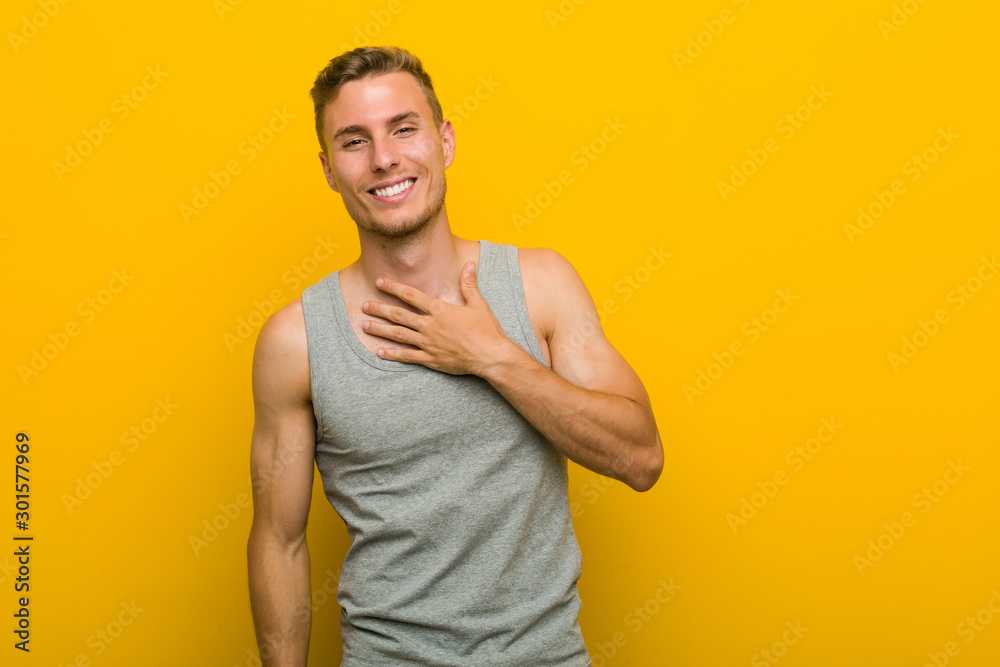 Young caucasian sport man laughs out loudly keeping hand on chest. Young caucasian sport man laughs out loudly keeping hand on chest.