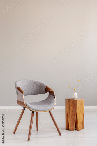 Stylish grey wooden chair in empty living room interior with trendy wooden coffee table photo
