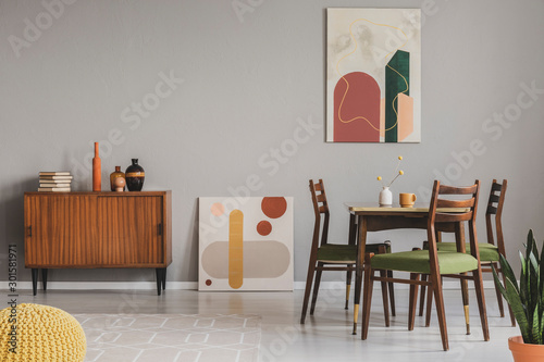 Vintage grey dining room with abstract paintings and wooden cupboard