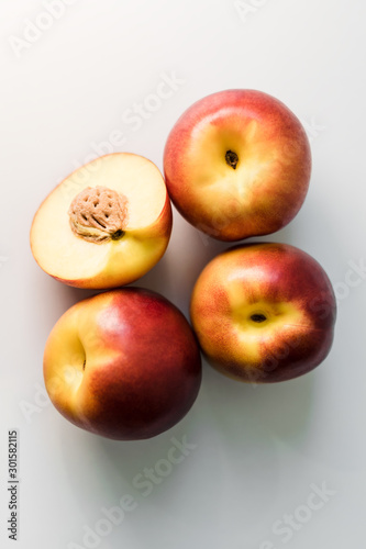 Ripe red, orange and yellow nectarines, peaches, apples on a white table. Tasty bright fruits. Healthy eating. Isolated object.