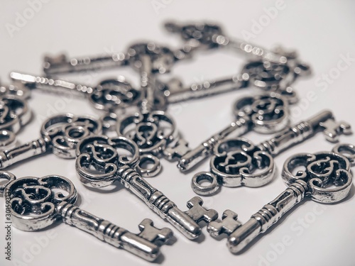 A lot of pendants in the form of keys on a white background. Materials for creating jewelry. Objects on a white background.