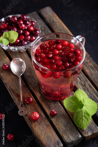 cranberry juice with honey in a cup, cranberries in sugar. On a dark wooden background