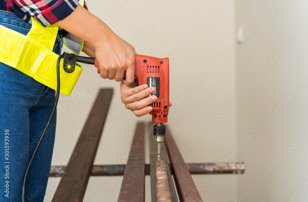 Close up hands of carpenter or technician or worker using power drill bit installing screwed a garage doors or door hinges House, Renovation Drilling Equipment Construction service concept