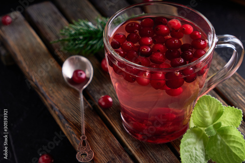 cranberry juice with honey in a cup, cranberries in sugar. On a dark wooden background Close up