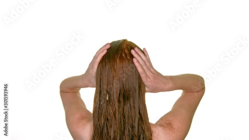 Young woman washing her long red hair, seen from behind photo