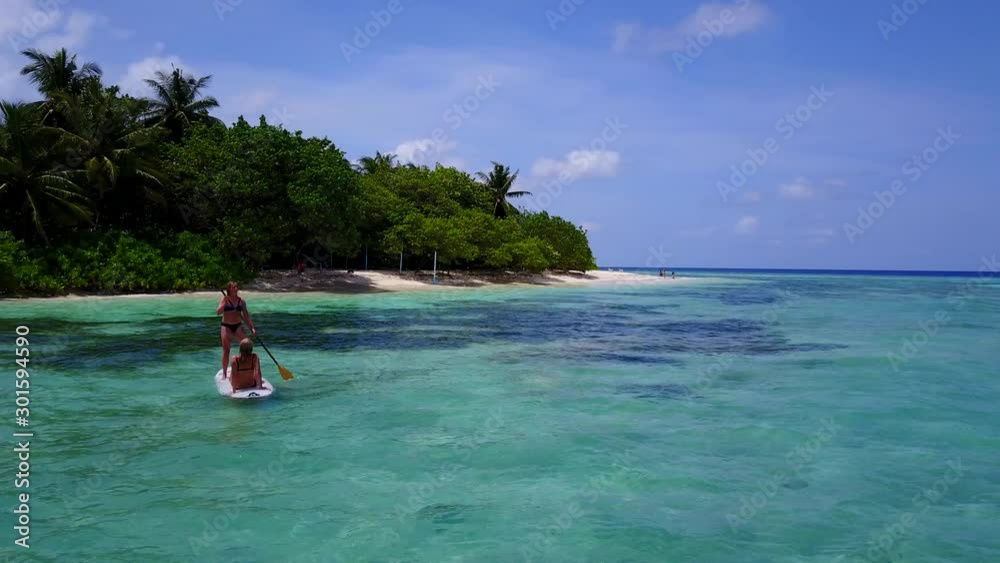 Girls in bikini in paddleboard floating at Bahamas Girls in bikini in paddleboard floating at Bahamas