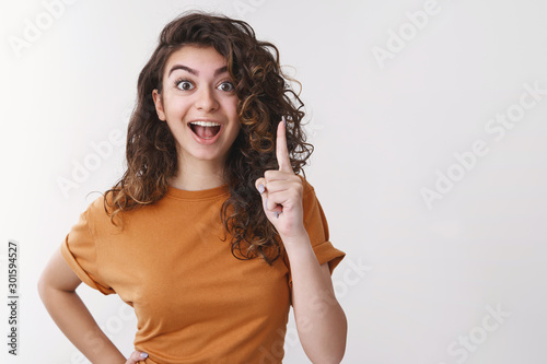 Girl have excellent idea. Portrait excited happy young woman share thoughts raise index finger eureka gesture smiling open mouth telling us awesome plan standing white background thrilled photo