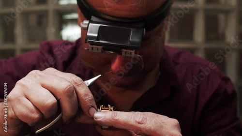 Old man bending claw or prong to secure stones on a gold ring