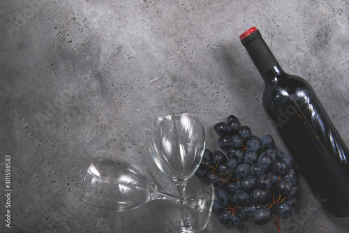 1 bottle of red wine, dark grapes, 1 glass on a gray background copy space,
