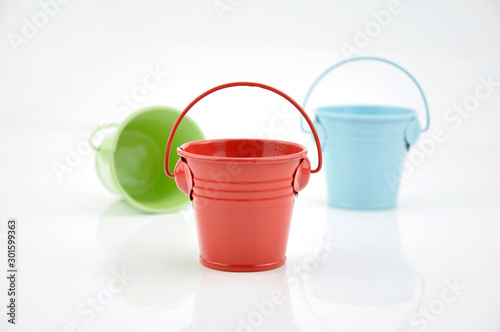 Three metal buckets of different colours with handle