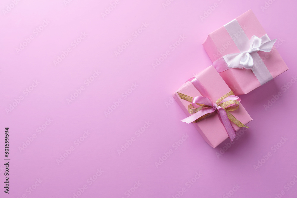 Presents, holiday traditions and shopping. Gift boxes in wrapping paper and tied with satin ribbon on pink background, copy space Presents, holiday traditions and shopping. Gift boxes in wrapping paper and tied with satin ribbon on pink background, copy space