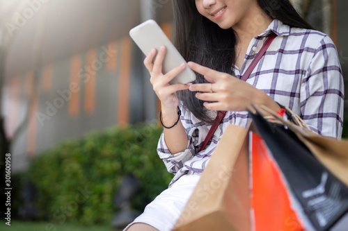 Young women holding smartphone and shopping bags. shopping online concept.