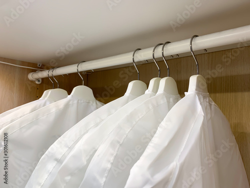 Clothes in covers hanging in wardrobe, safe clothing storage © Nadezhda