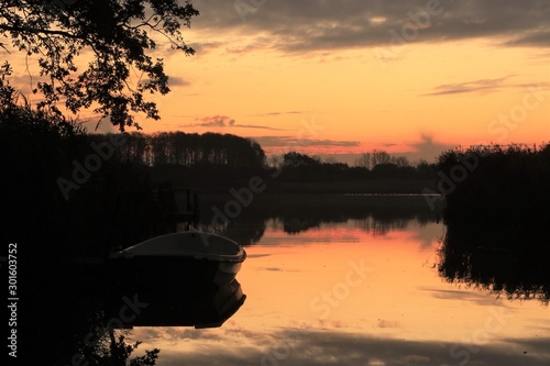 idyllic lake side scenery with row boat at dawn