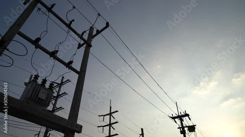 moving forward and looking up along high voltage transformer electrical line silhouette with bright blue sky and cloudy weather in evening time stock footage