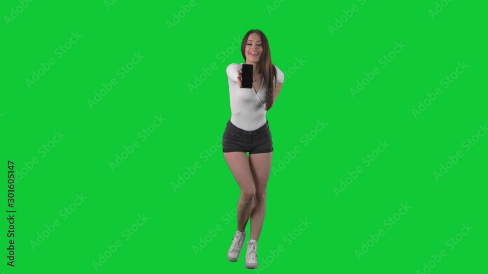 Attractive sexy young woman showing and advertising blank smart phone screen. Full body over green screen background. Attractive sexy young woman showing and advertising blank smart phone screen. Full body over green screen background.