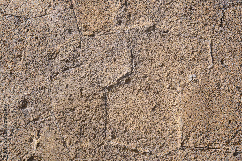 Fragment of an old stone wall of an ancient Roman temple made of processed sandstone. Background. The color of ocher.