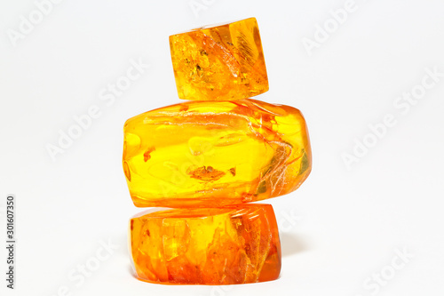 Three transparent yellow pieces of amber on a white background. Composition of sun stone. Inclusions and insects in an ancient resin of a tree. Crystals. Semi-precious mineral for jewelers. Material 