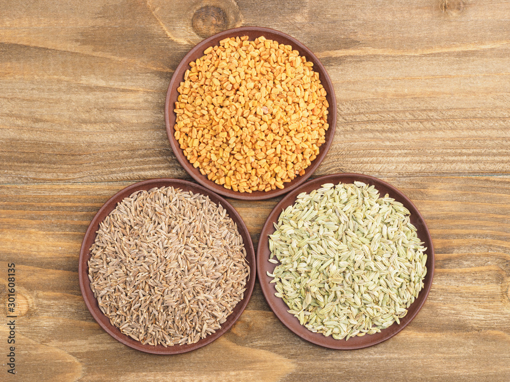 Cumin, fennel, fenugreek on brown wooden background. Indian cuisine, ayurveda, naturopathy concept Cumin, fennel, fenugreek on brown wooden background. Indian cuisine, ayurveda, naturopathy concept