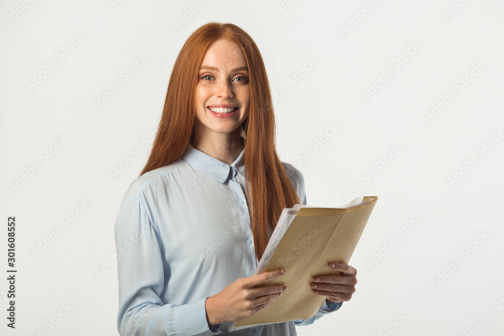 beautiful young woman with red hair with a folder of documents in hand beautiful young woman with red hair with a folder of documents in hand