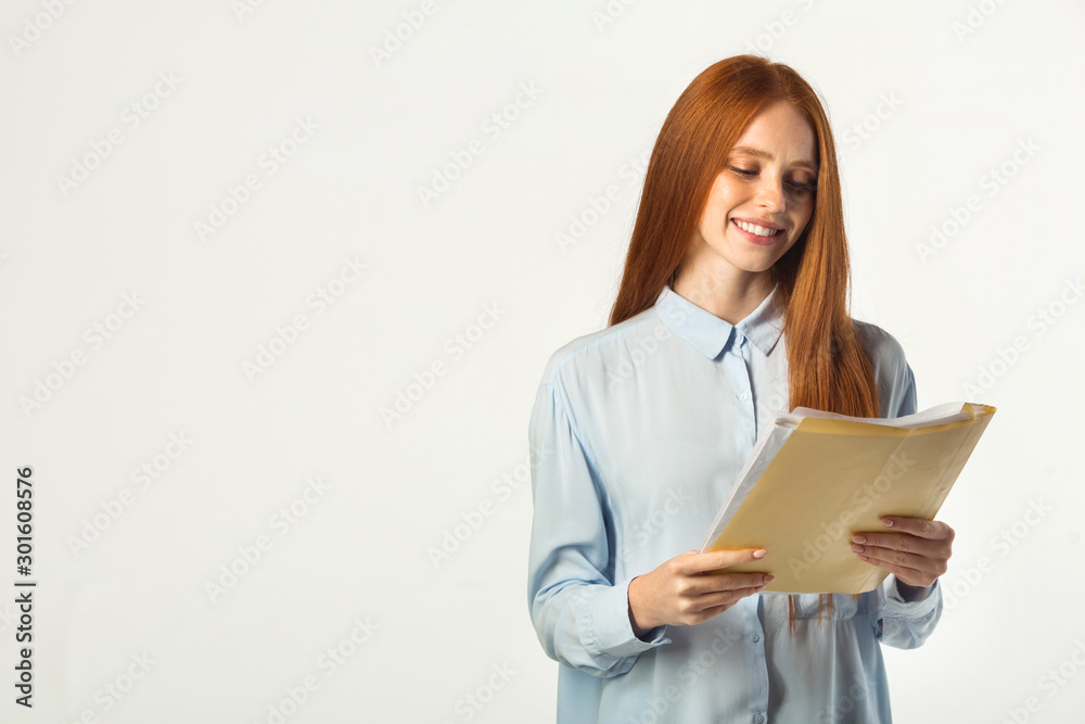 beautiful young woman with red hair with a folder of documents in hand beautiful young woman with red hair with a folder of documents in hand