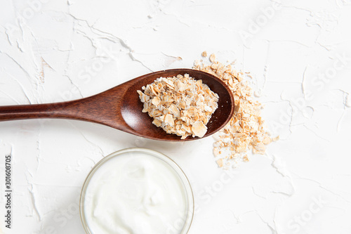 Homemade cosmetics with yogurt and oatmeal on a white background. Ingredients for the mask photo