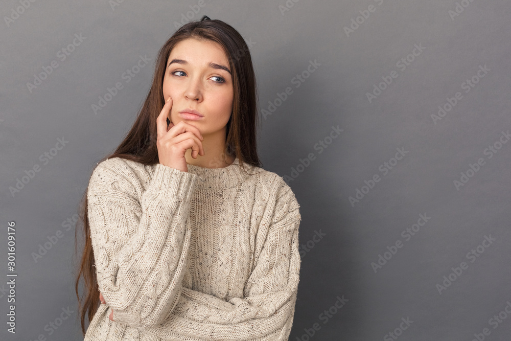 Looking for Solution. Young woman in sweater standing studio isolated on grey looking aside pensive Looking for Solution. Young woman in sweater standing studio isolated on grey looking aside pensive
