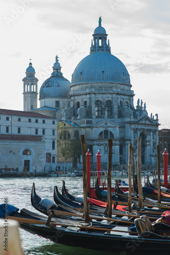Traditional venetian gondolas by the waterfront. Several boats for travelers and tourists are covered with covers at the pier.