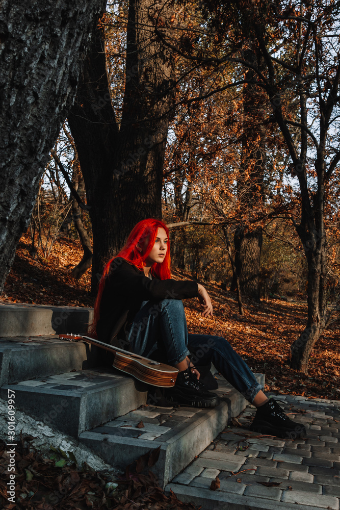 Sexy beautiful redhead girl with magnificent long hair. Ukulele playing, sitting on the steps in the park. Perfect woman portrait. Musical education, street performer. Sexy beautiful redhead girl with magnificent long hair. Ukulele playing, sitting on the steps in the park. Perfect woman portrait. Musical education, street performer.